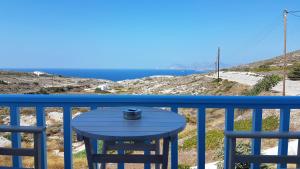 a blue table on a balcony with a view of the ocean at Sarakiniko Rooms in Adamantas