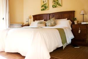 a bedroom with a large bed with white sheets and pillows at Hospedería El Pico del Fraile in Cobreros