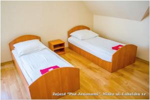 two beds in a small room with wooden floors at Zajazd Pod Jesionami in Nisko