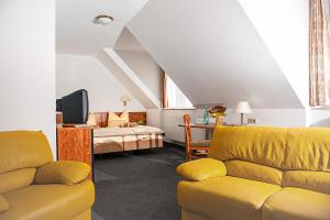 a living room with a yellow couch and a bed at Hotel Zum Hirsch in Römhild