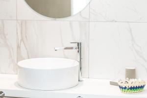 bagno bianco con lavandino e specchio di Ark 68 City Rooms a Rethymno
