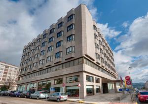 een hoog gebouw met auto's geparkeerd voor het bij Hotel Vigo Los Galeones Affiliated by Meliá in Vigo