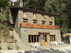 un bâtiment avec des tables et des chaises devant lui dans l'établissement Hostal Les Roquetes, à Queralbs