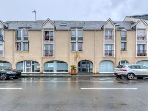 um edifício de apartamentos com carros estacionados num parque de estacionamento em Apartment in a residence by the sea em Port-en-Bessin-Huppain