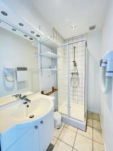 a white bathroom with a shower and a sink at Residence Louis Place du Marche in Bains-les-Bains