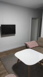 a living room with a white table and a tv on a wall at Apartman A&E in Živinice