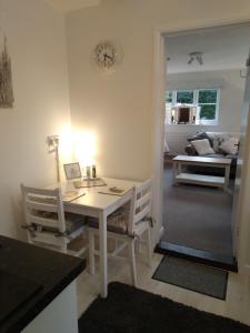 a kitchen with a white table and chairs and a room at Brick Kiln Apartment in Campsey Ash