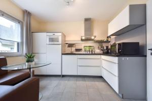 a kitchen with white cabinets and a glass table at Ferienhaus Seestrand - mit Sauna in Kolpinsee
