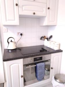 a kitchen with white cabinets and a stove top oven at Brick Kiln Apartment in Campsea Ashe