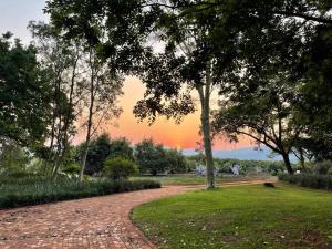 een bakstenen pad in een park met een zonsondergang op de achtergrond bij Boschoek Farm in Tzaneen