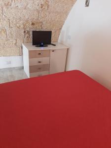 Zimmer mit einem roten Teppich und einem Schreibtisch mit einem TV. in der Unterkunft Casa di Carmine 2 in Galatina
