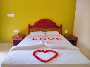 a bedroom with a bed with two hearts on it at Kayaloram Resort in Pūvār