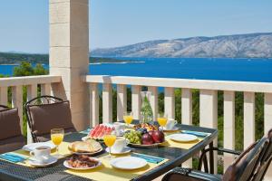 een tafel met eten op een balkon met uitzicht op de oceaan bij Hvaretta Villas in Stari Grad