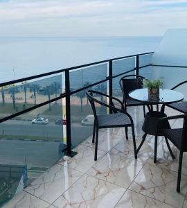 balcón con mesa, sillas y vistas al océano en sea view rooms in Batumi en Batumi
