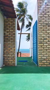 una puerta azul en el lateral de una casa con una palmera en Cabanas Caraúbas, en Maxaranguape