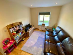 uma sala de estar com um sofá de couro e uma televisão em Torrans Cottage em Downings