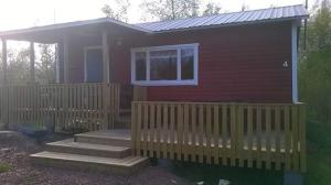 een klein rood huis met een veranda en een raam bij Sommarö Stugor in Föglö