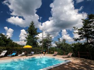 a swimming pool with chairs and a yellow umbrella at Belvilla by OYO Villa Sole in Misciano