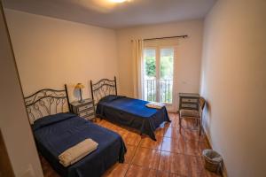 Un dormitorio con dos camas y una ventana. en Calle Cruz, en Jubrique