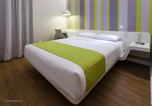 ein Schlafzimmer mit einem großen Bett mit einer gelben und grünen Decke in der Unterkunft DMax Hotel in Marília