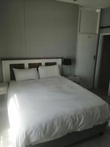 un lit avec des draps blancs et des oreillers dans une chambre dans l'établissement Seagull 512, à Margate