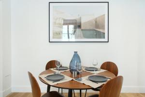 einen Esstisch mit Stühlen und ein Bild an der Wand in der Unterkunft Apartment Palais Royal by Studio prestige in Paris