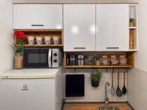 eine Küche mit weißen Schränken und einer Mikrowelle in der Unterkunft Studio Central Square in Gospić