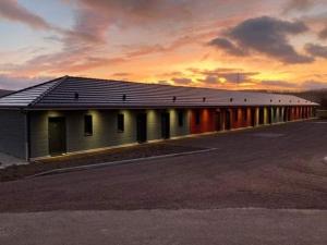 un edificio largo con una puesta de sol en el fondo en Hôtel MAAS en Montigny-le-Roi