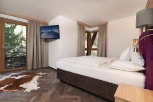 a hotel room with a large bed and a tv at Hotel Gundolf in Sankt Leonhard im Pitztal