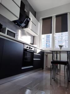 een keuken met zwarte apparatuur en een tafel met stoelen bij Luxury City Center Apartment – Garofita Romana in Boekarest
