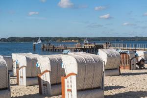 a row of chairs on a beach with a pier at Ferienwohnung Storchennest in Hürup