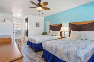 een slaapkamer met 2 bedden, een tafel en een plafondventilator bij Malibu Resort Motel in St Pete Beach