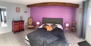 una camera con un letto con una parete viola di Auberge Saint Fergeux a Gionges