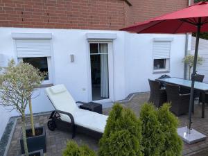 a patio with a white chair and a red umbrella at Ferienwohnung Andres in Wees