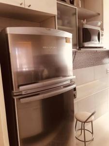 a stainless steel refrigerator in a kitchen with a stool at Aconchegante e prático in Campinas