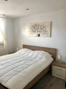 1 cama blanca en un dormitorio con una foto en la pared en Ferienhaus De Blauwe Reiger Ferienpark Vislust Ijsselmeer, en Wervershoof