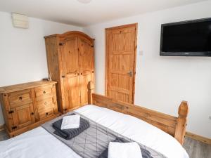 a bedroom with a bed and a flat screen tv at Cranford House in Alford