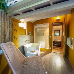 a bathroom with a tub and a chair and a table at Vila deste Hotel in Búzios