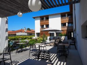 un patio avec tables, chaises et un parasol dans l'établissement Hotel Restaurant Santiago, à Hendaye
