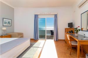a hotel room with a bed and a desk and a computer at Hotel Maritur - Adults Only in Albufeira
