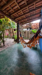 a hammock hanging under a porch with water at Hospedaria Caraíva in Caraíva