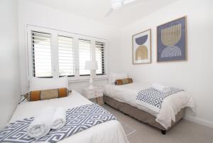 2 letti in una camera da letto con pareti e finestre bianche di 1002 Bermudas - by Stay in Umhlanga a Durban