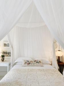 a white bedroom with a bed with a canopy at The Richmond Café and Rooms in Richmond