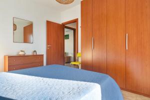 a bedroom with a blue bed and wooden cabinets at Appartamento Cristallo by BarbarHouse in Torre Lapillo