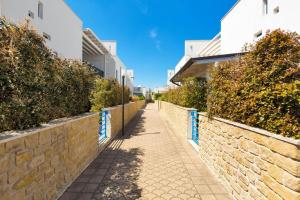 a sidewalk next to a brick wall with bushes at Appartamento Cristallo by BarbarHouse in Torre Lapillo
