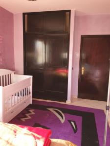 um quarto para bebés com um berço e uma porta preta em Appartement al fadl em Marrakech