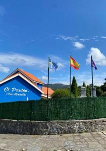 una valla con banderas delante de un edificio en Apartamentos El Pradón, en Cudillero