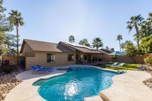 een zwembad met blauwe stoelen en een huis bij Scottsdale Friess home in Scottsdale