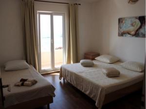 two beds in a room with a large window at Apartments Anita in Cavtat