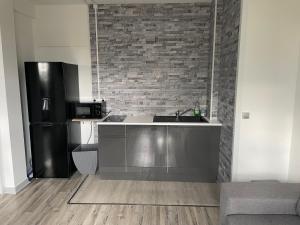 a kitchen with a sink and a black refrigerator at Family Hôtel FUTUROSCOPE in Jaunay-Clan